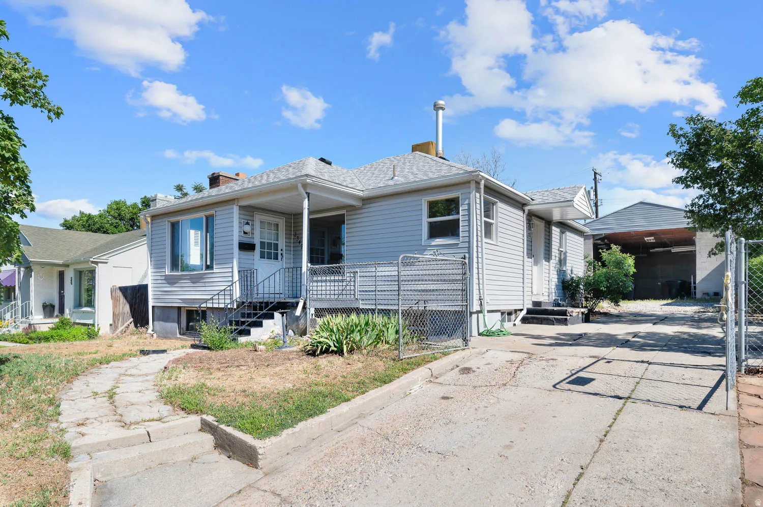 Ranch-style exterior with light gray siding, covered front porch, and a dedicated driveway