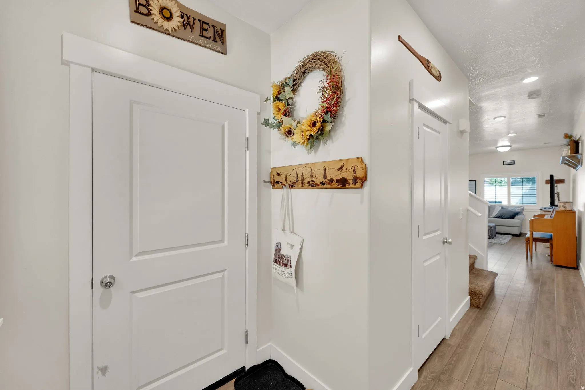 Entryway featuring a white paneled door with brushed nickel hardware, light wood-finish flooring, white baseboards, and recessed lighting