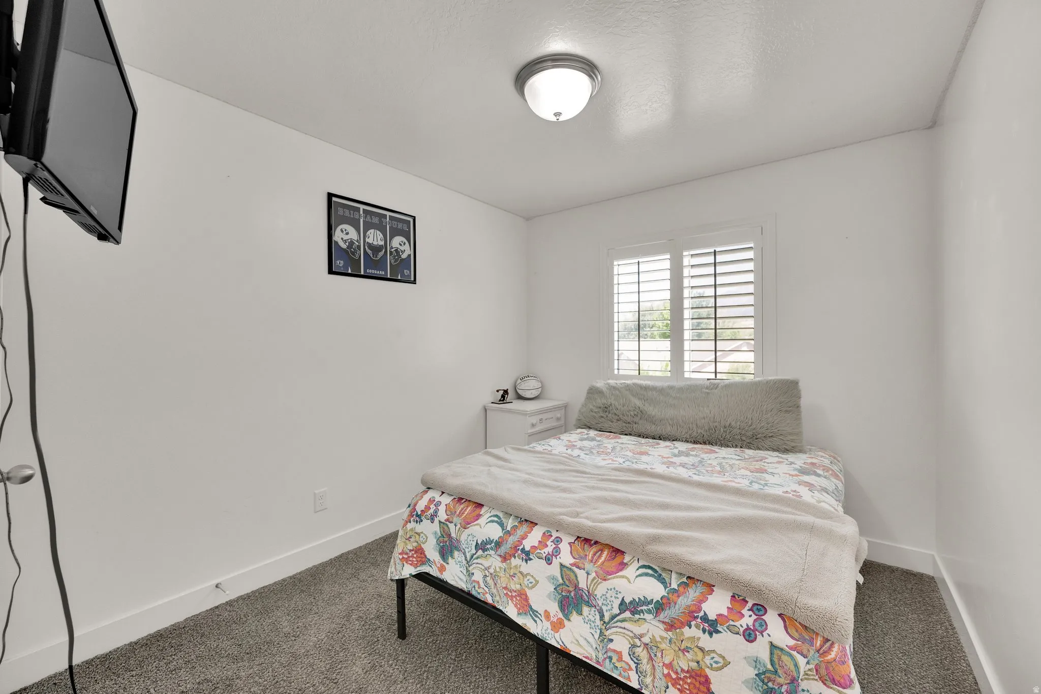 Room featuring neutral wall paint, carpet flooring, a window with plantation shutters, white baseboards, and a semi-flush mount ceiling light fixture