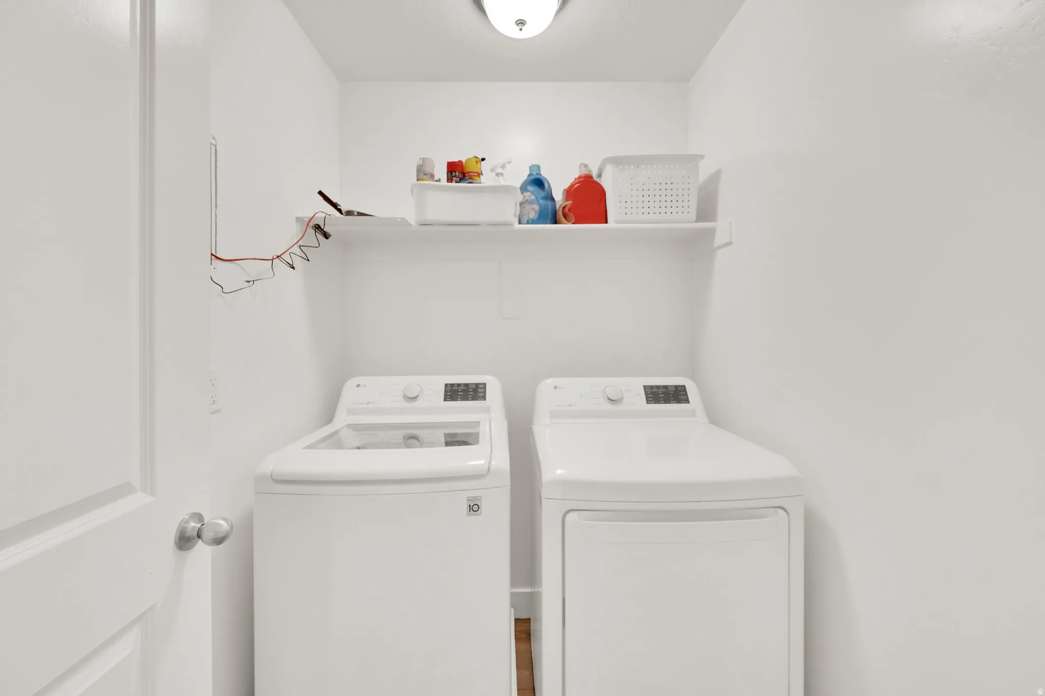 Dedicated laundry space featuring a white top-load washing machine and white dryer unit