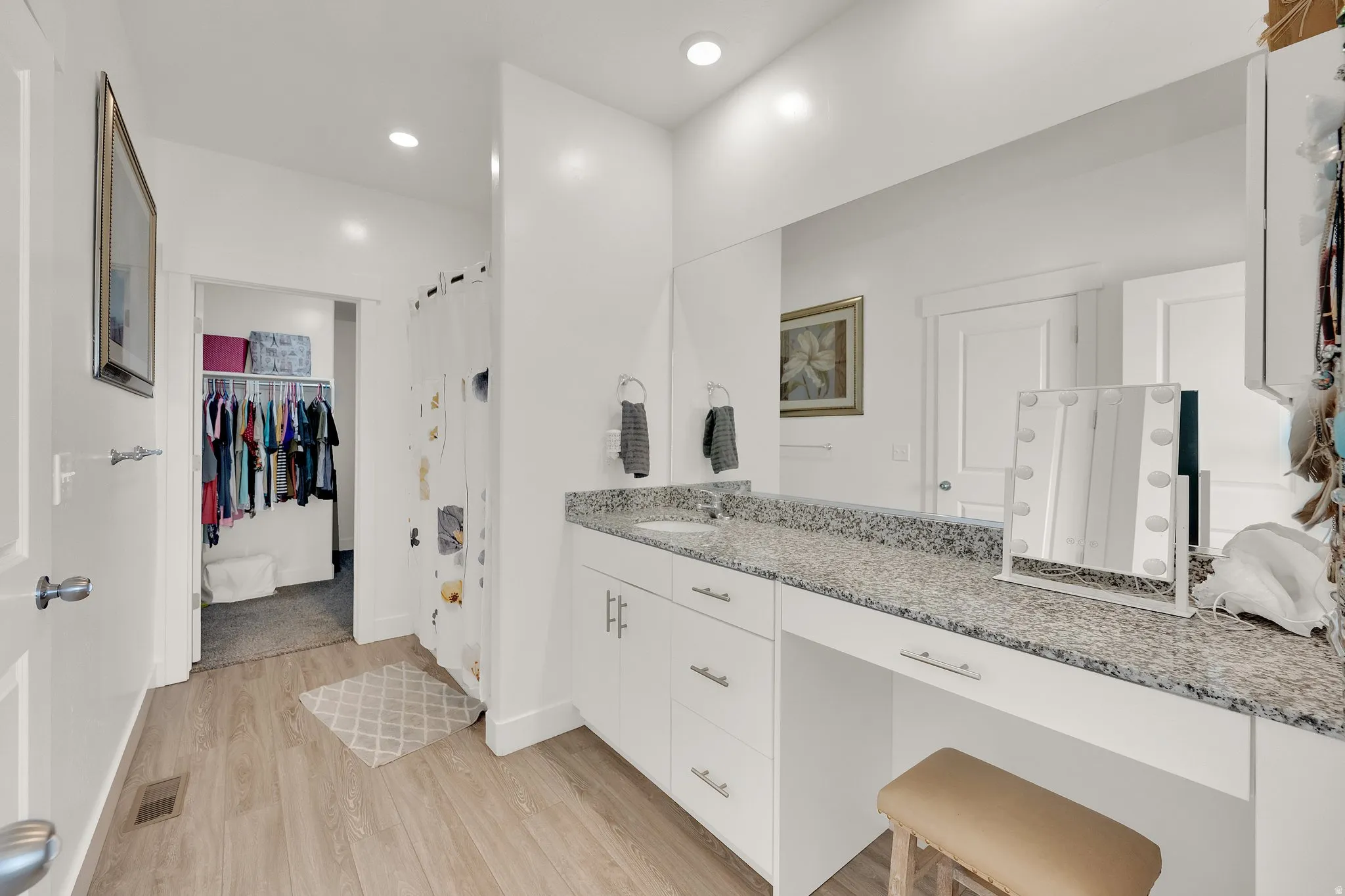 Bathroom vanity featuring a light-toned wood-finish floor and a spacious countertop with a built-in sink
