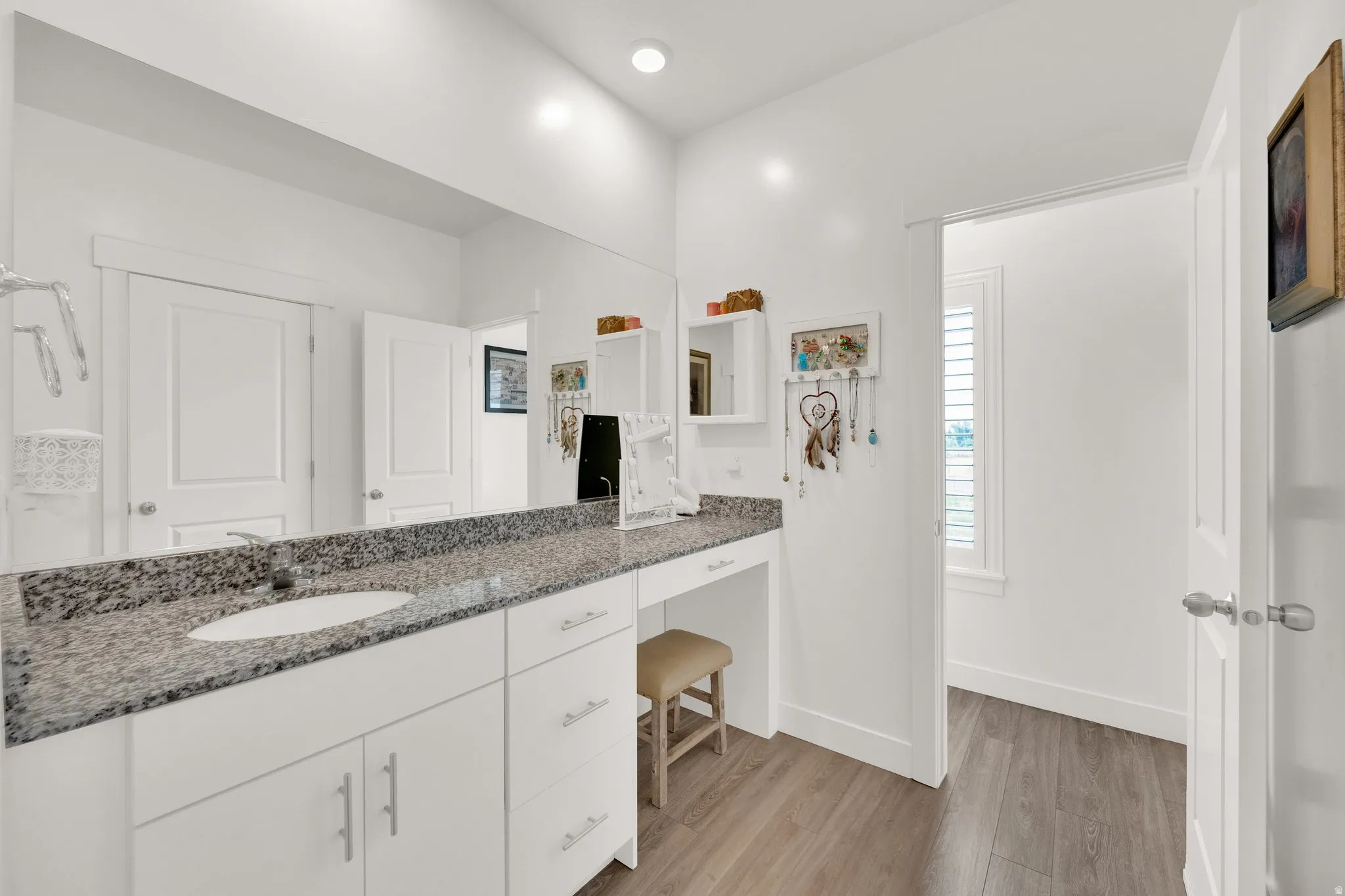 Modern vanity featuring a granite-style countertop, integrated single sink, and white cabinetry with brushed nickel hardware