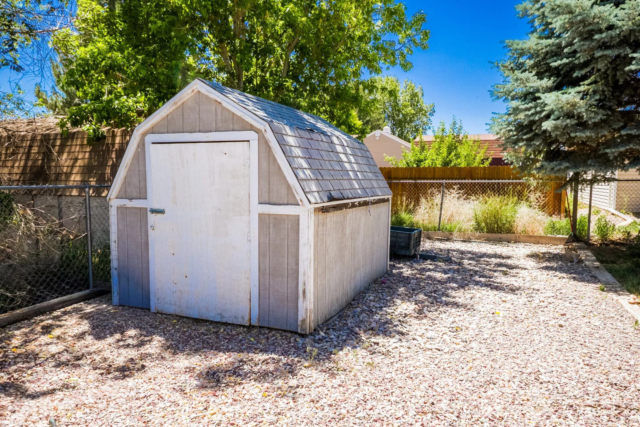 Gable roof shed with a single door entry, situated on a gravel surface