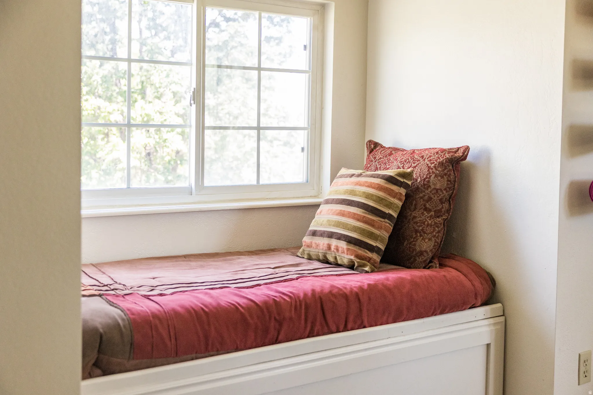 Integrated window seat featuring a large gridded window, white trim, and light-colored walls