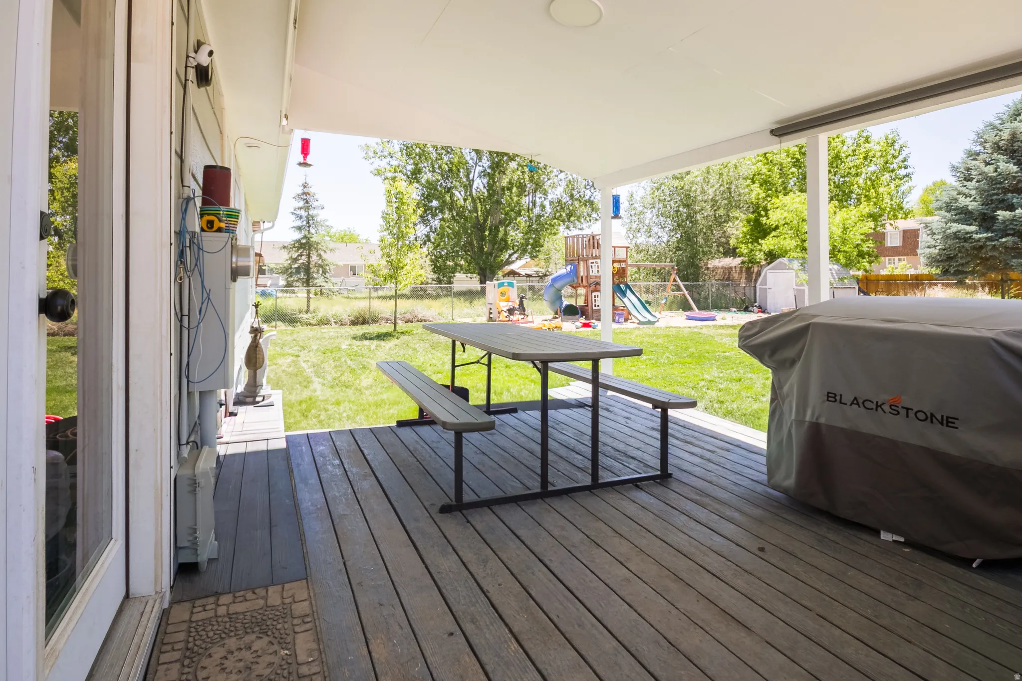 Covered deck with wood-finish flooring extending to a spacious grass yard