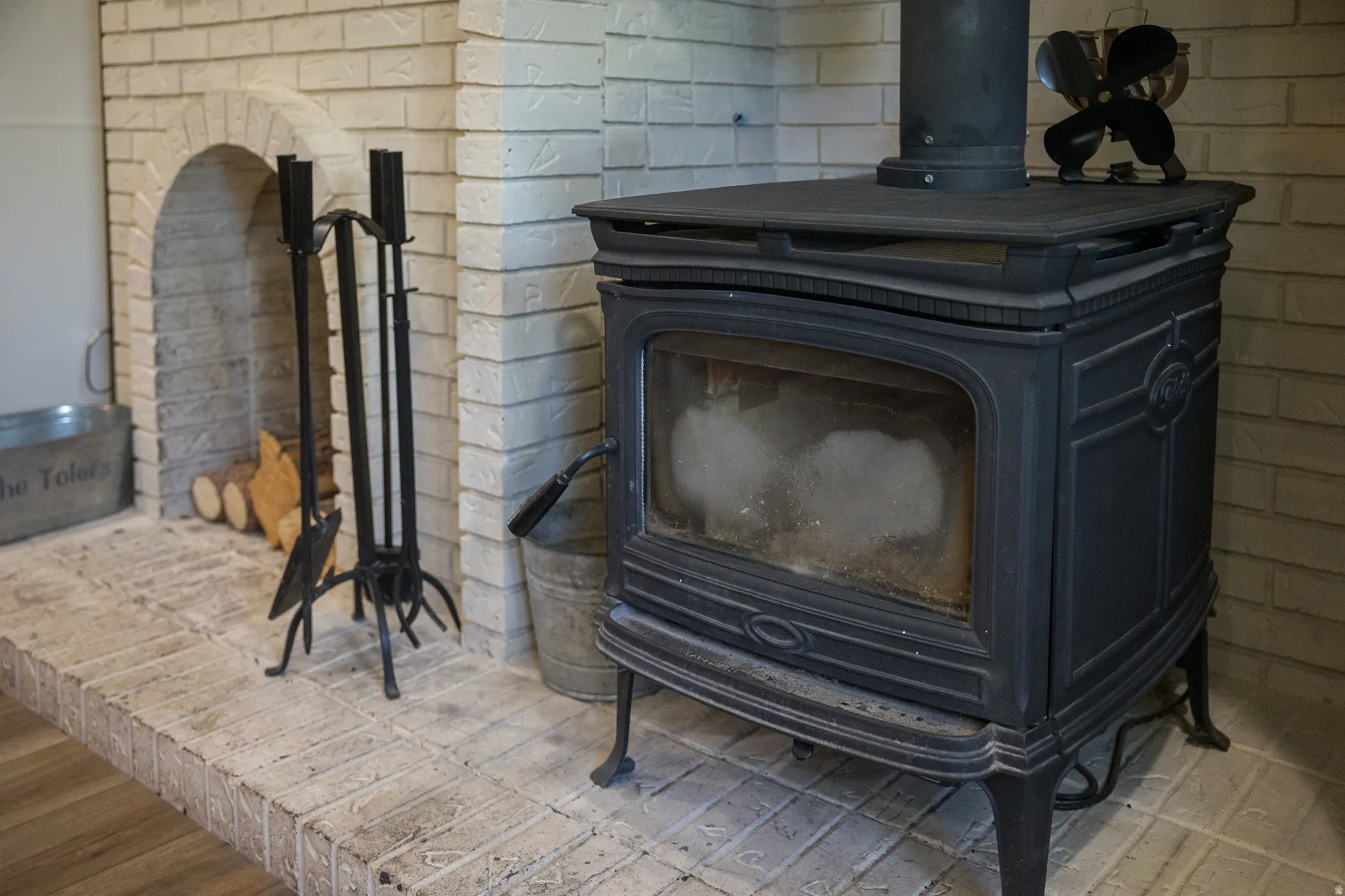 Cast iron wood-burning stove set on a light-colored brick hearth
