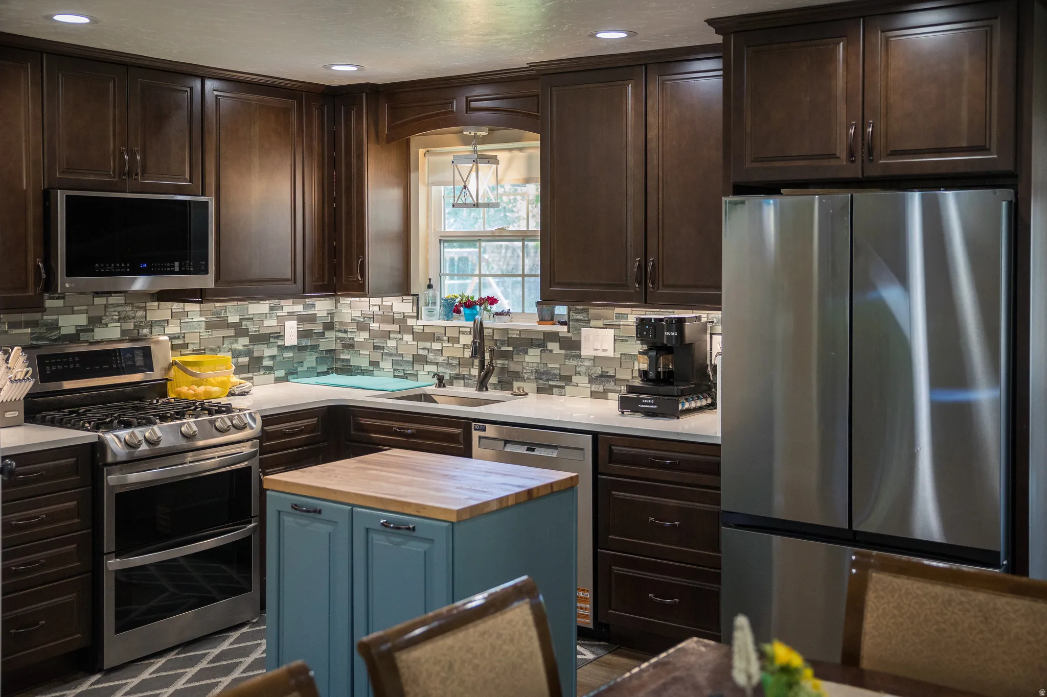 Kitchen featuring dark wood-finish cabinetry, light countertops, and a mosaic tile backsplash