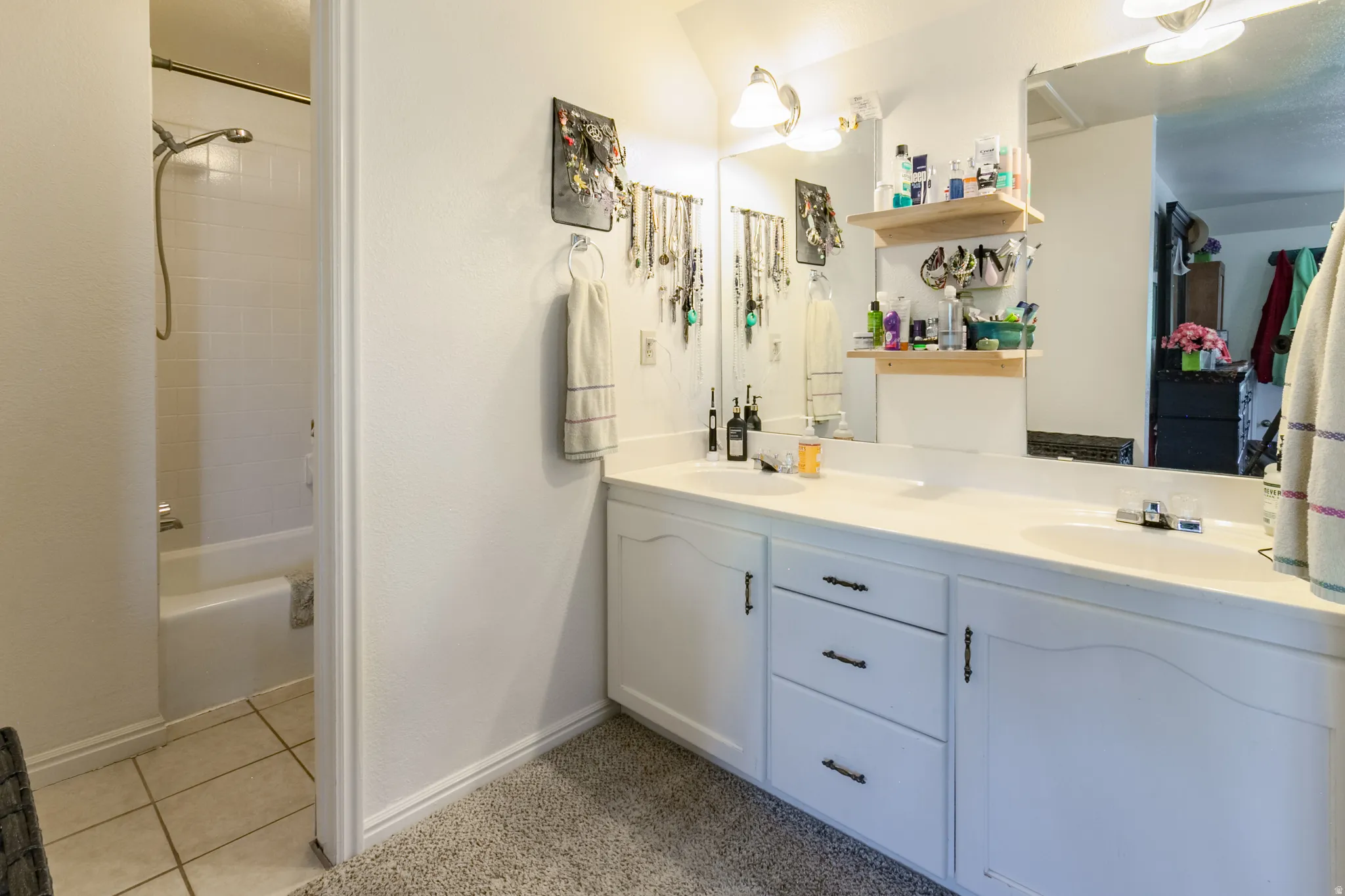 Bathroom featuring a double vanity with integrated sinks, white cabinetry, and brushed nickel hardware