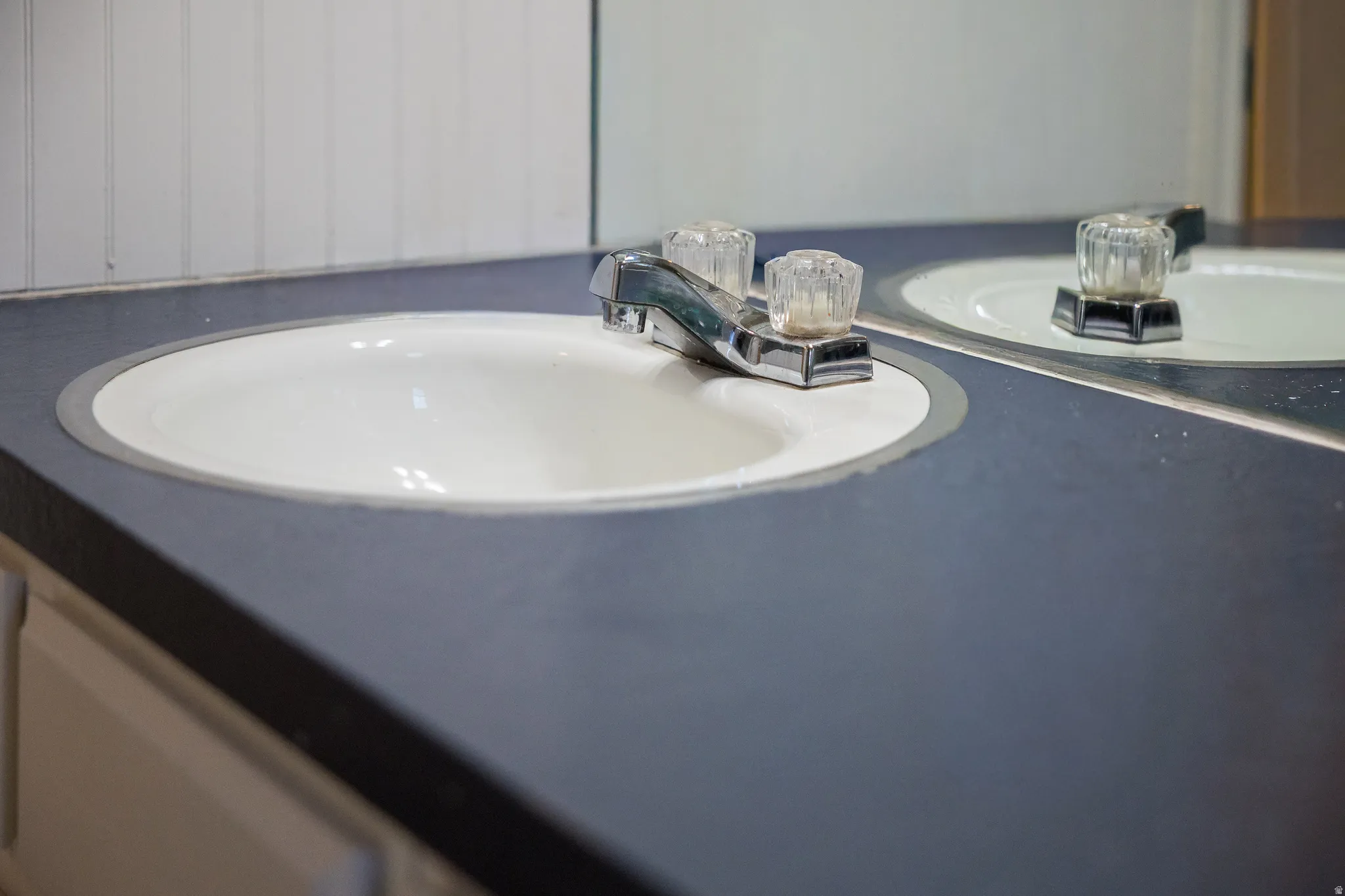 Double vanity with integrated white sinks, chrome faucets, and a dark countertop