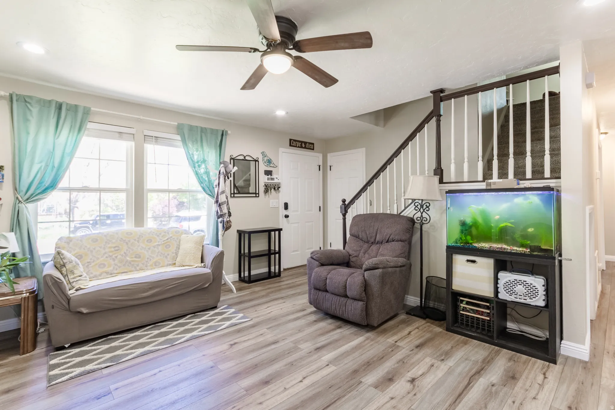 Living area with wood-finish flooring, a ceiling fan, and recessed lighting