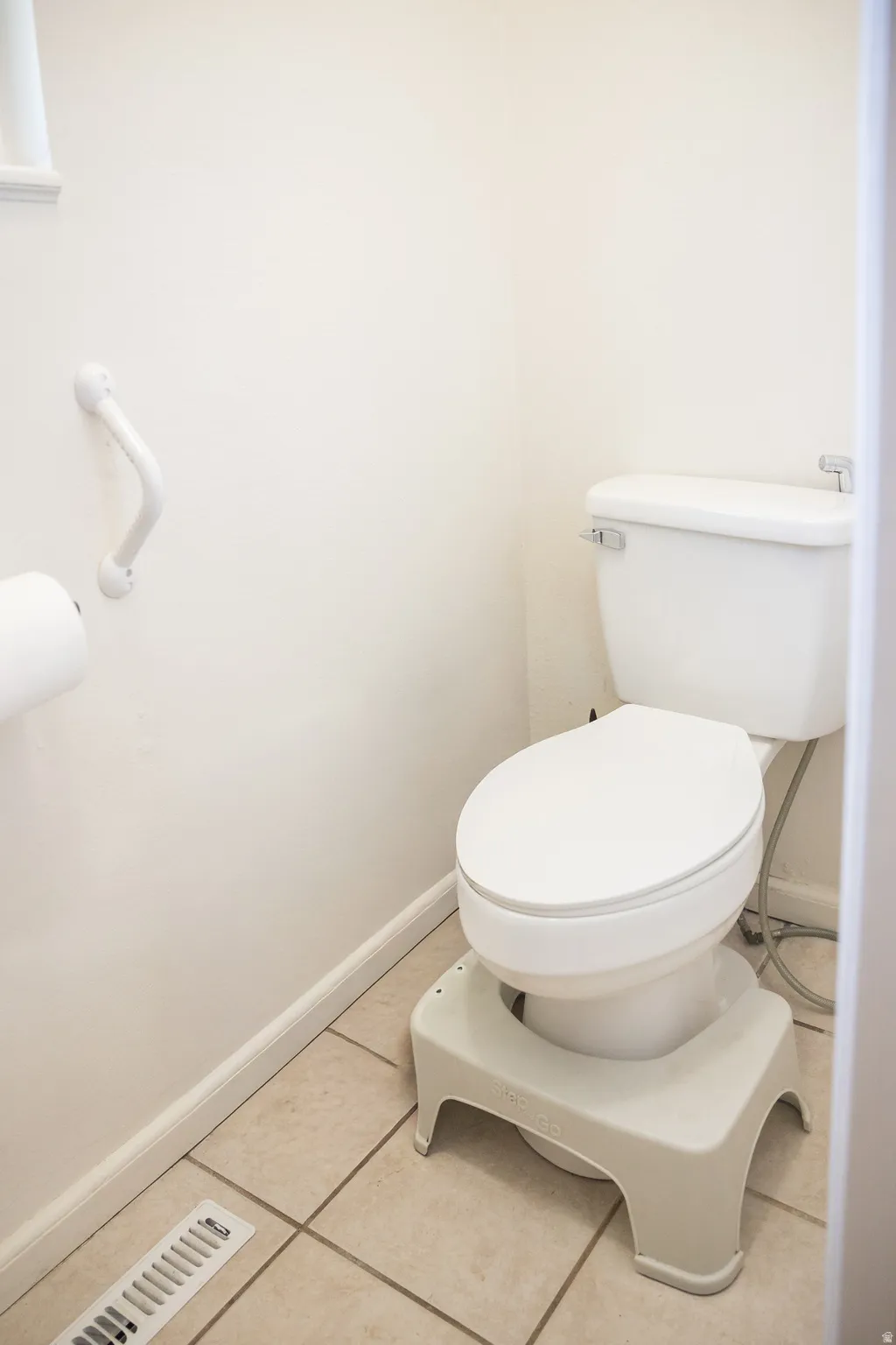 Full white ceramic toilet with chrome lever flush and white grab bar