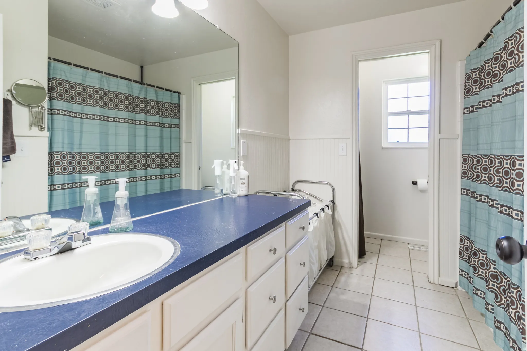 Bathroom featuring a blue countertop vanity with integrated sink, white cabinetry, and a large wall-mounted mirror