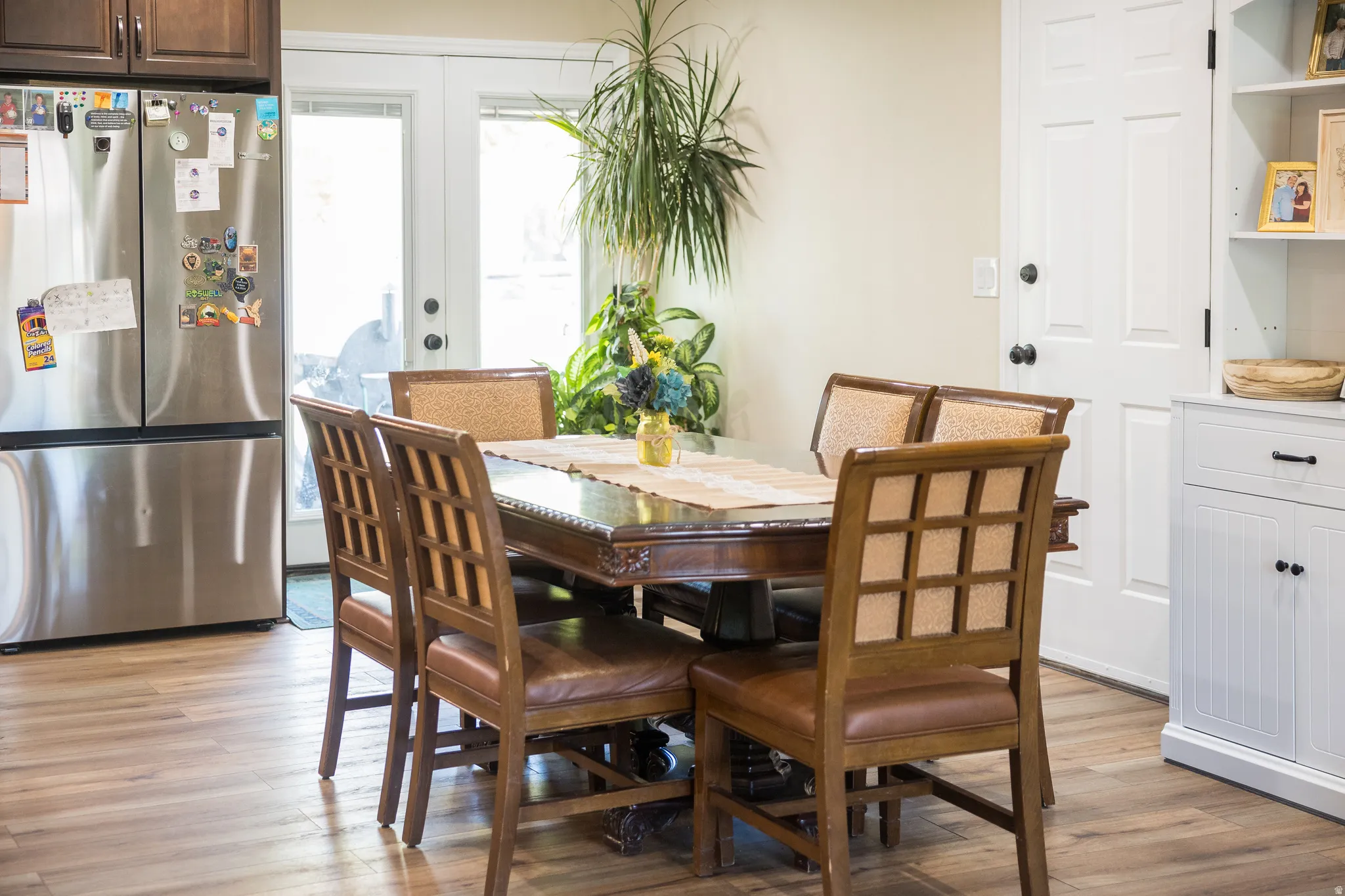 Dining area featuring wood-finish flooring, a double-door exterior entry, and a built-in white cabinet with shelving