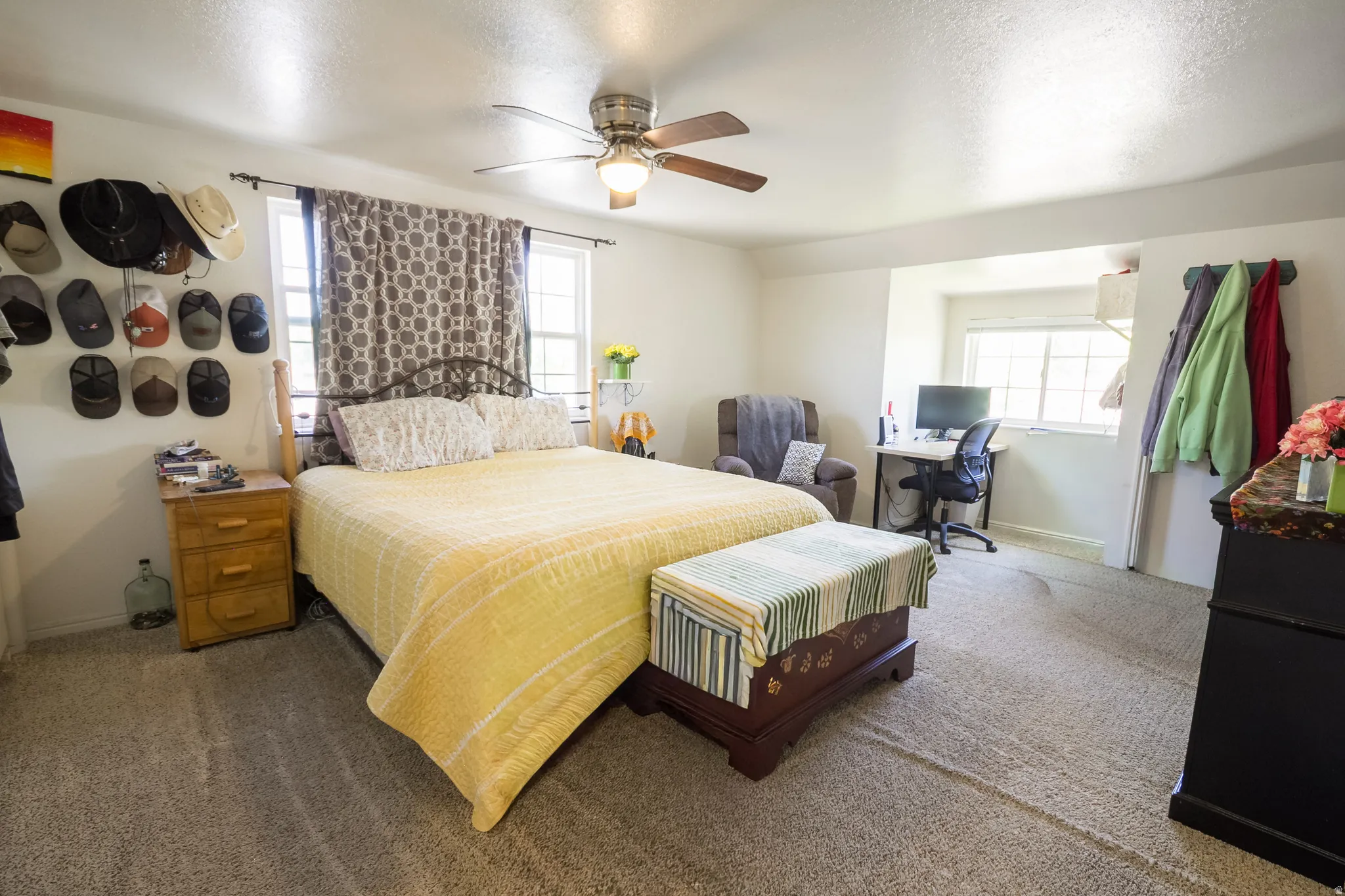 Carpeted room featuring multiple windows, a ceiling fan with integrated lighting, and a built-in recessed area