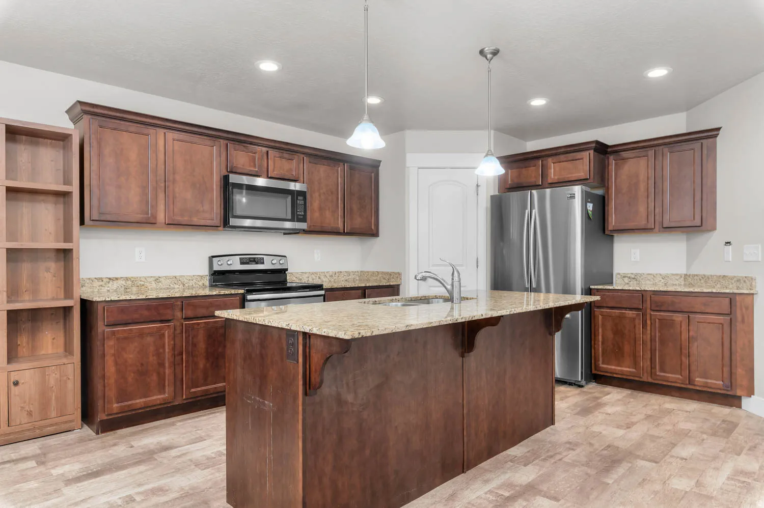 Kitchen featuring wood-finish flooring, dark wood cabinetry, and light-toned countertops