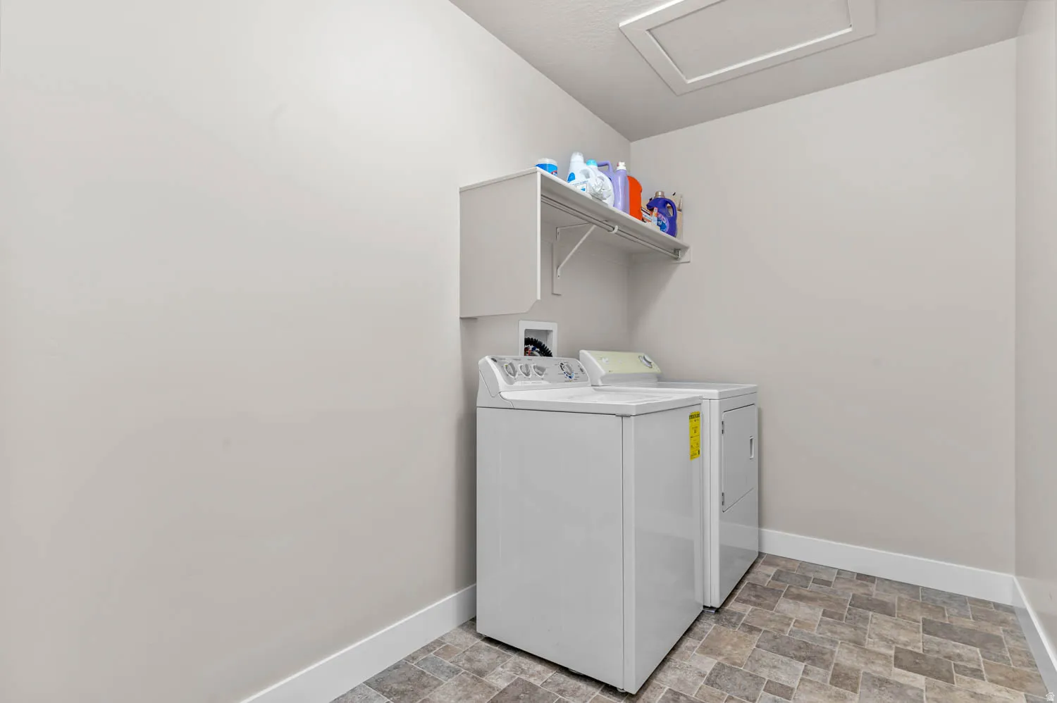 Dedicated laundry area featuring a patterned floor, light-colored walls, and a built-in overhead shelf for storage
