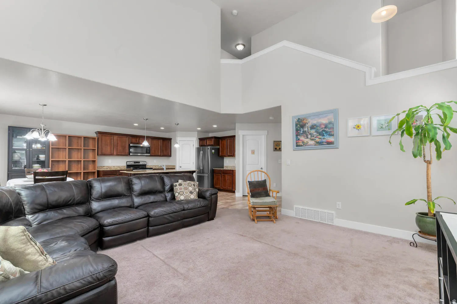 Spacious open-concept living area featuring light-toned carpeting and vaulted ceilings