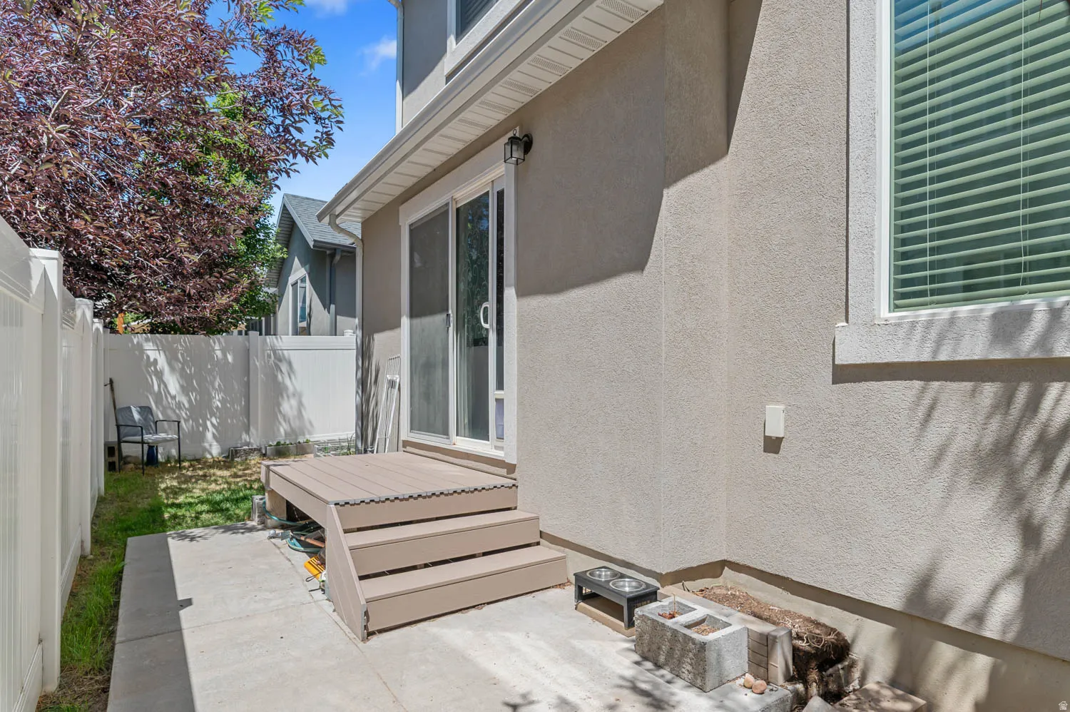 Private backyard area featuring a composite deck with steps, a sliding glass door entry, and a concrete patio