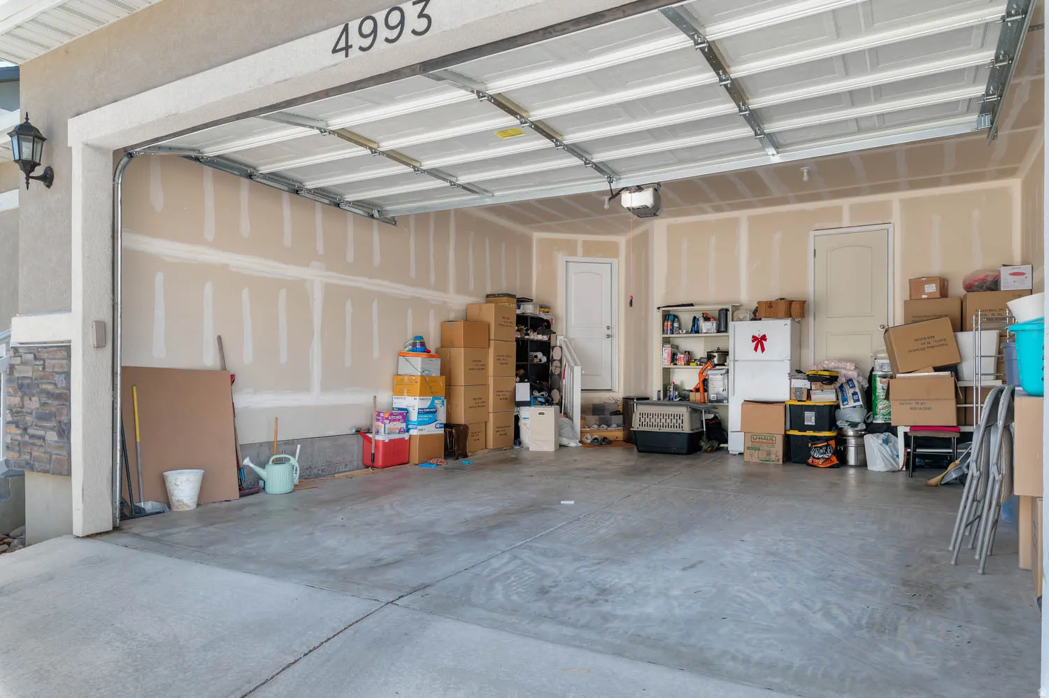 Spacious two-car garage with an automatic overhead door, concrete flooring, and two interior access doors