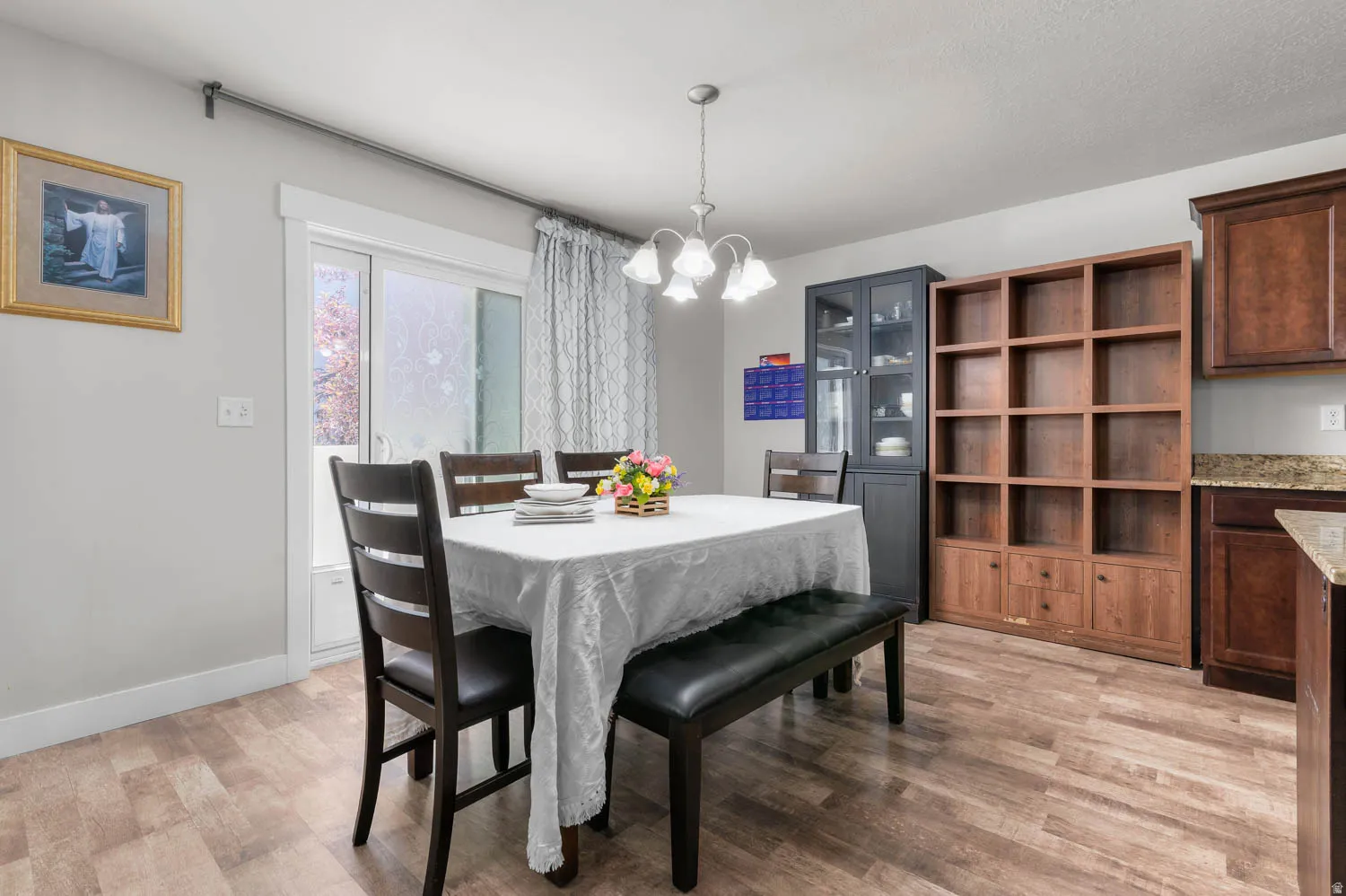 Dining area featuring wood-finish flooring, a sliding glass door, overhead chandelier lighting, and a neutral wall color