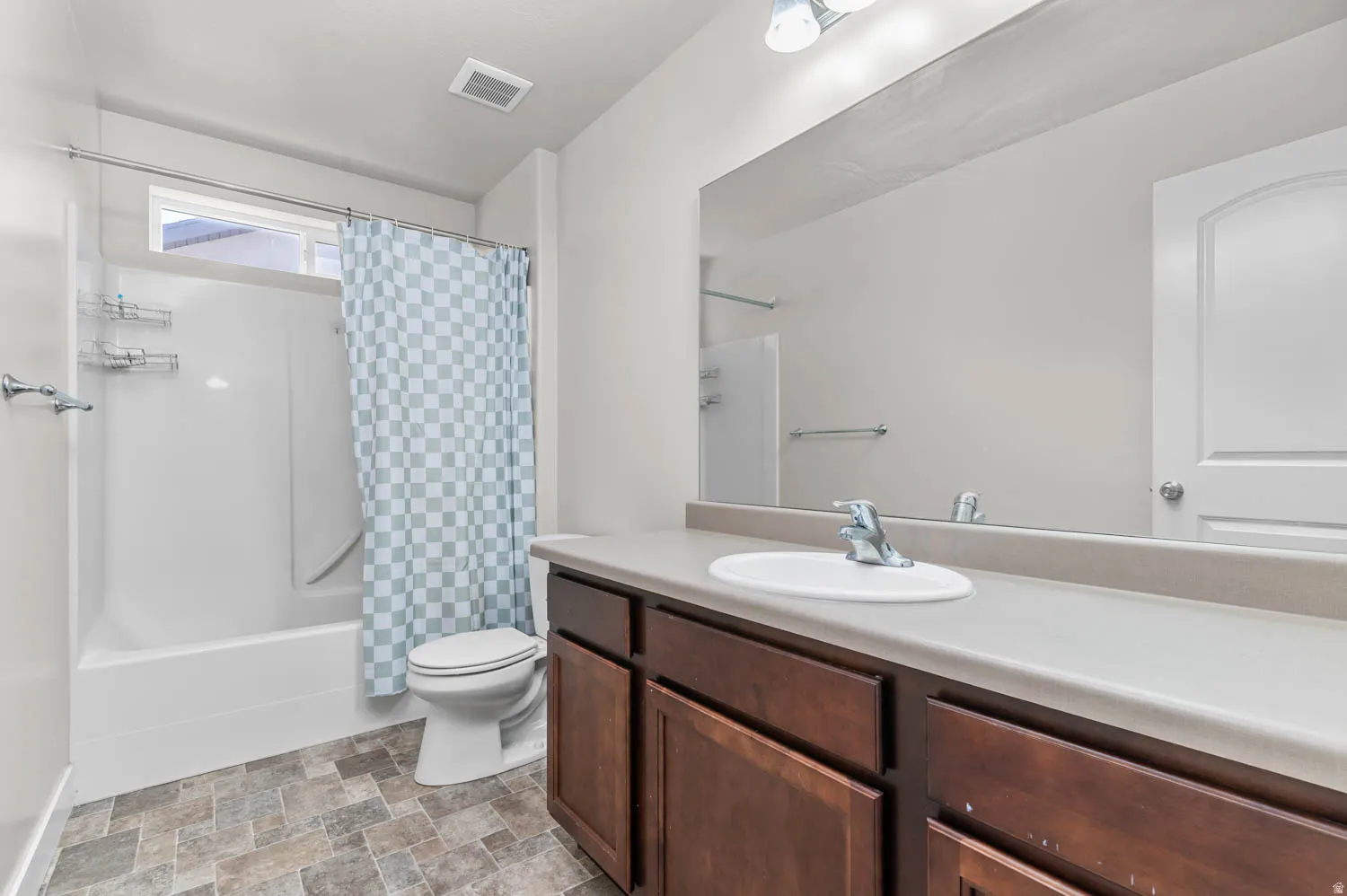 Bathroom featuring a spacious vanity with an integrated sink, an expansive mirror, and a white tub/shower combination