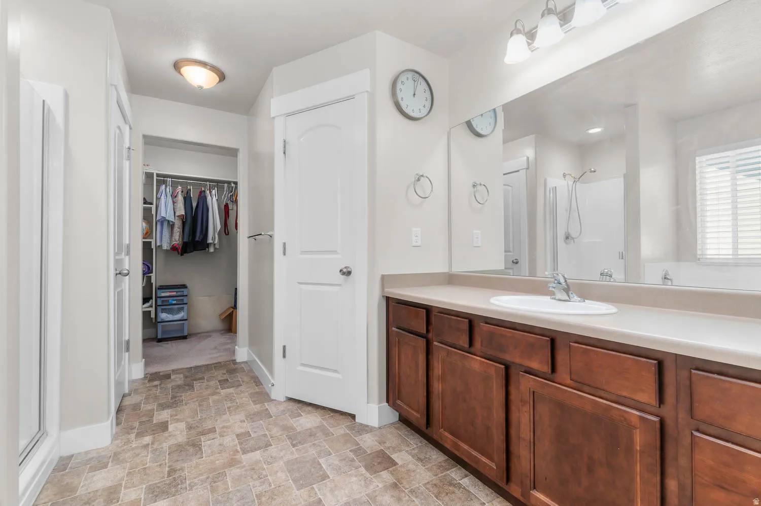 Bathroom featuring a light-toned countertop, a single undermount sink, and a large vanity mirror