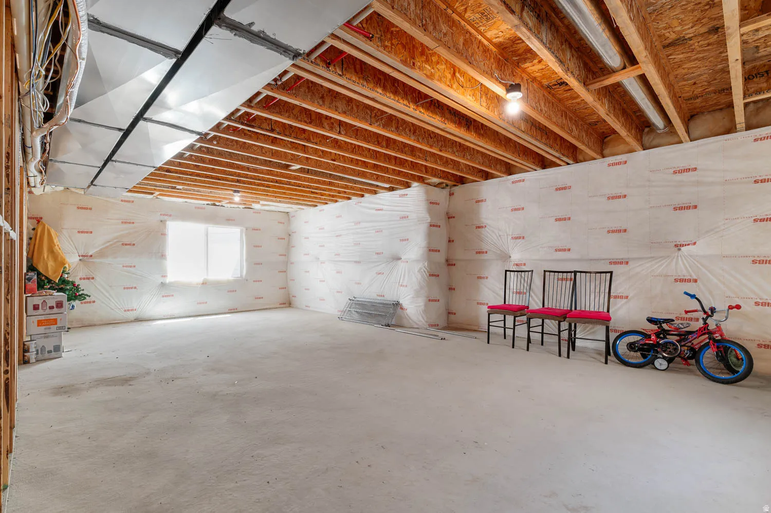 Unfinished lower level with exposed wood joists and concrete flooring