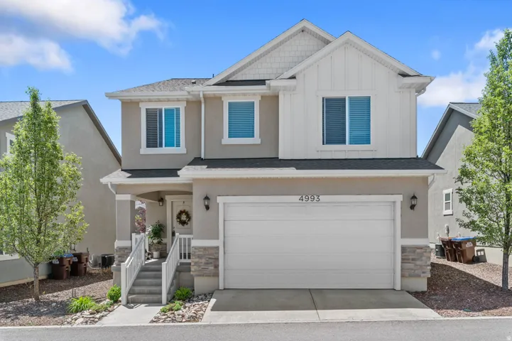 Contemporary two-story residence with a two-tone facade, featuring a full-width garage door