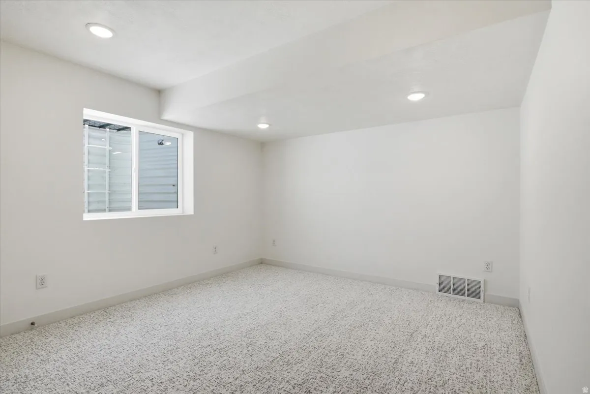Room featuring recessed lighting, light-toned carpeting, white walls, and a white-framed window