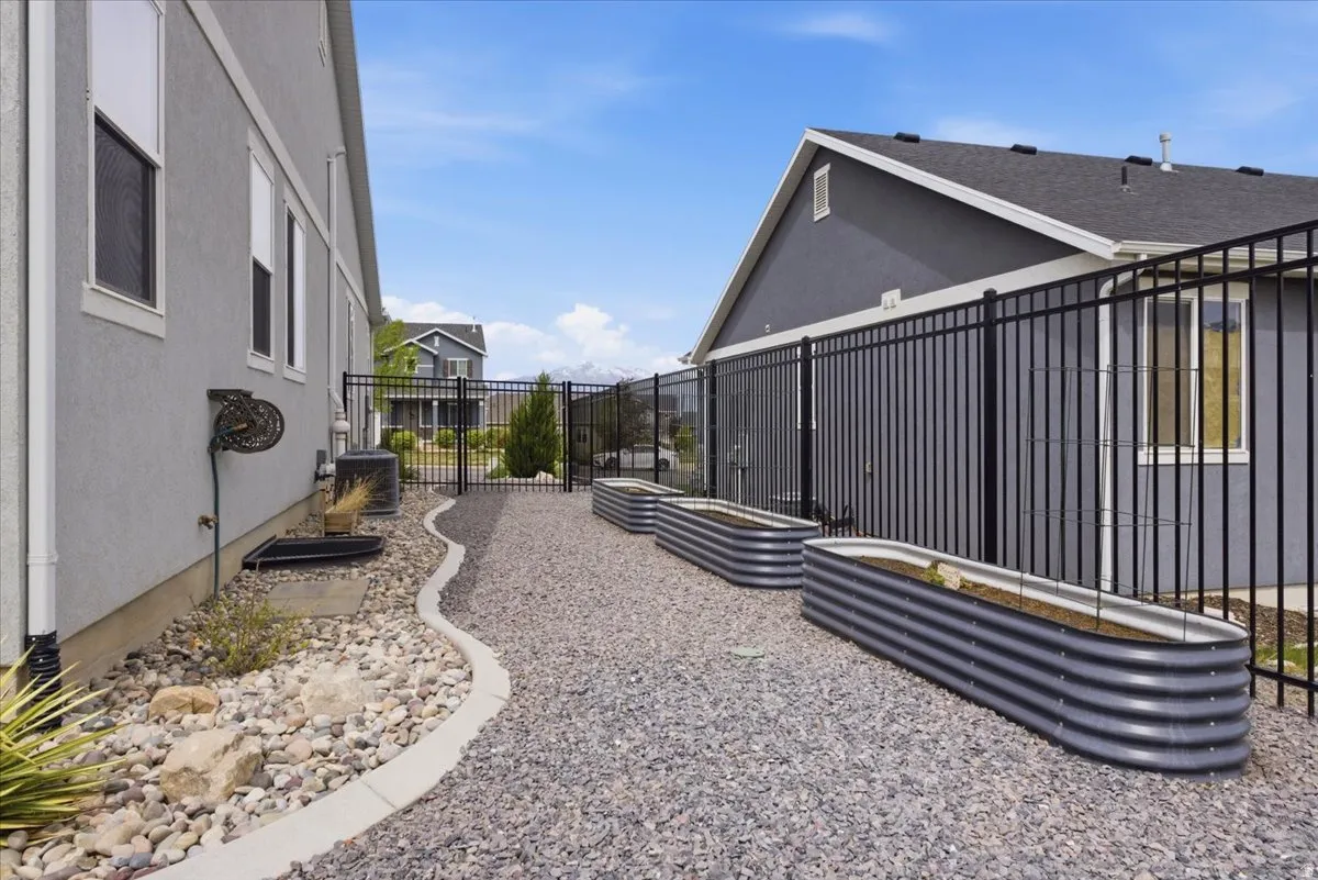 Landscaped side yard featuring gravel ground cover and three corrugated metal raised garden beds