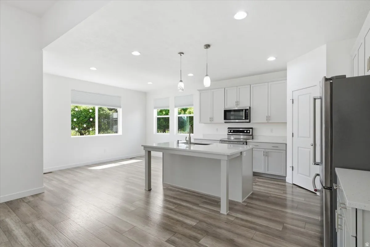 Spacious open-concept area featuring wood-finish flooring, recessed lighting, and large windows