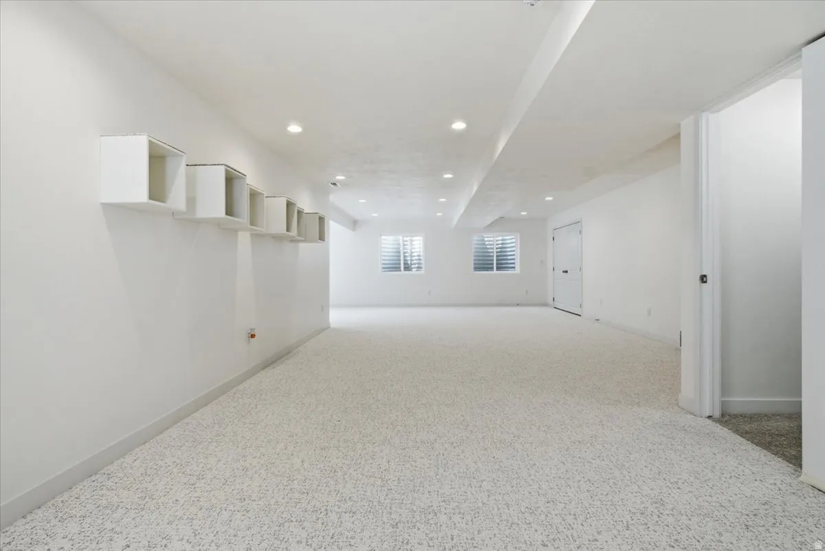 Spacious room featuring light-toned carpeting, recessed lighting, and white walls