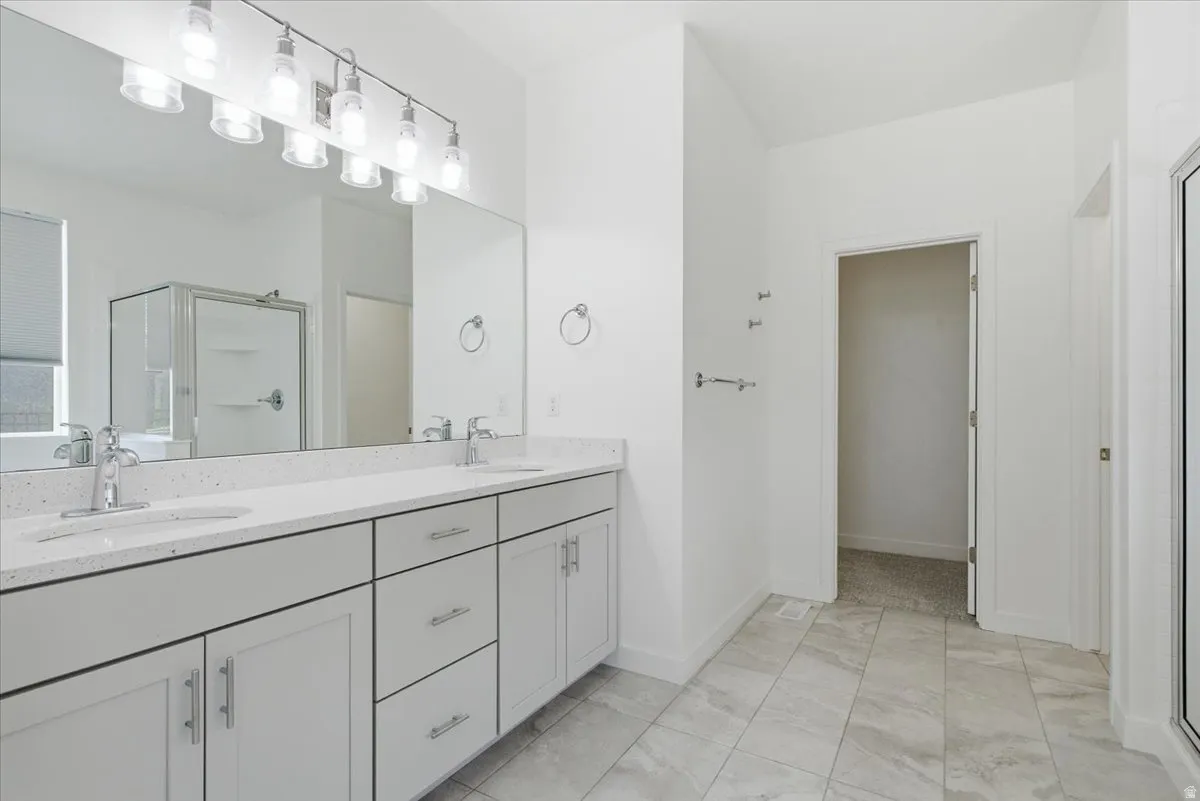Dual vanity with light gray cabinetry, chrome hardware, and a speckled white countertop