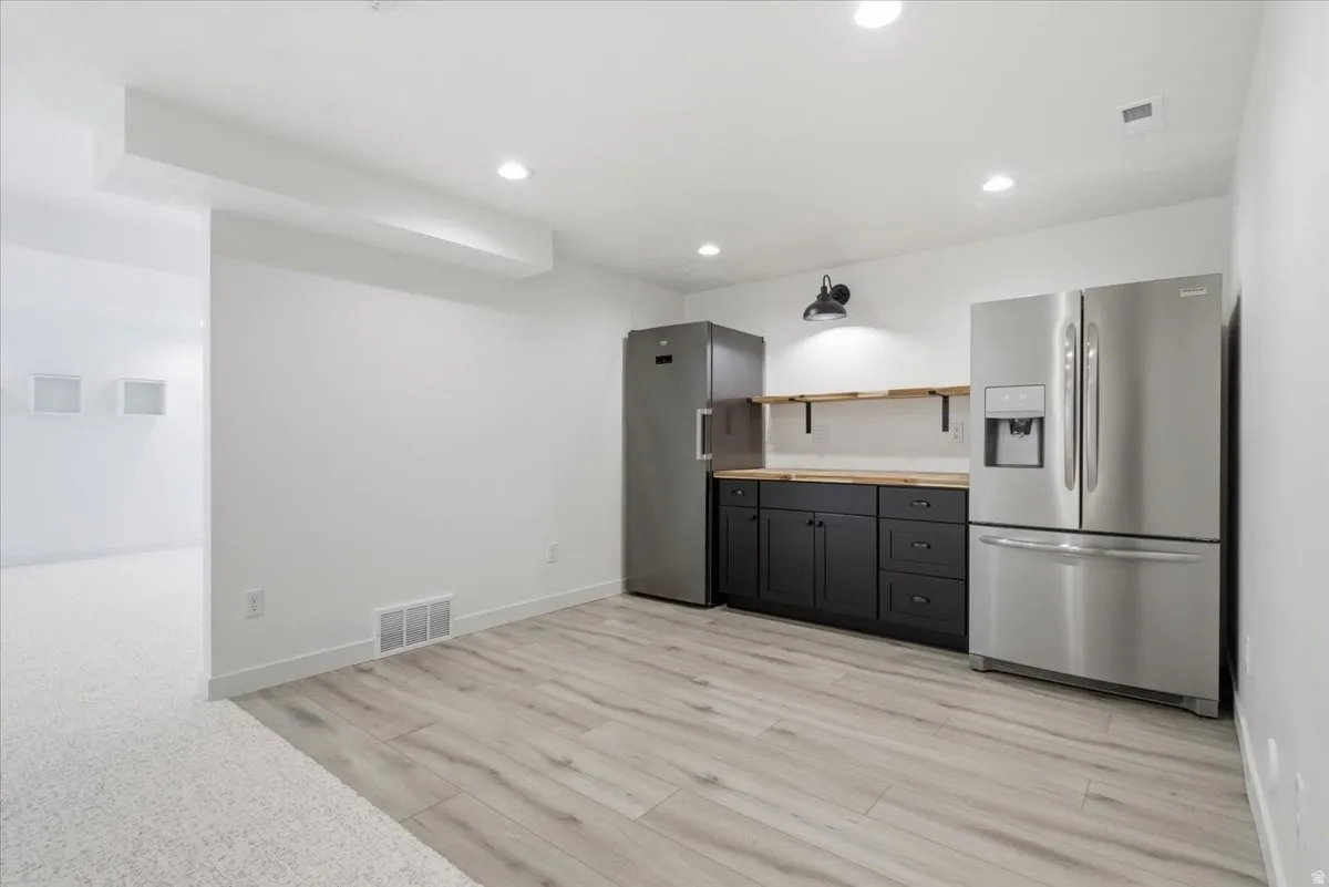 Kitchenette featuring stainless steel appliances, black base cabinetry, wood countertops, and open shelving