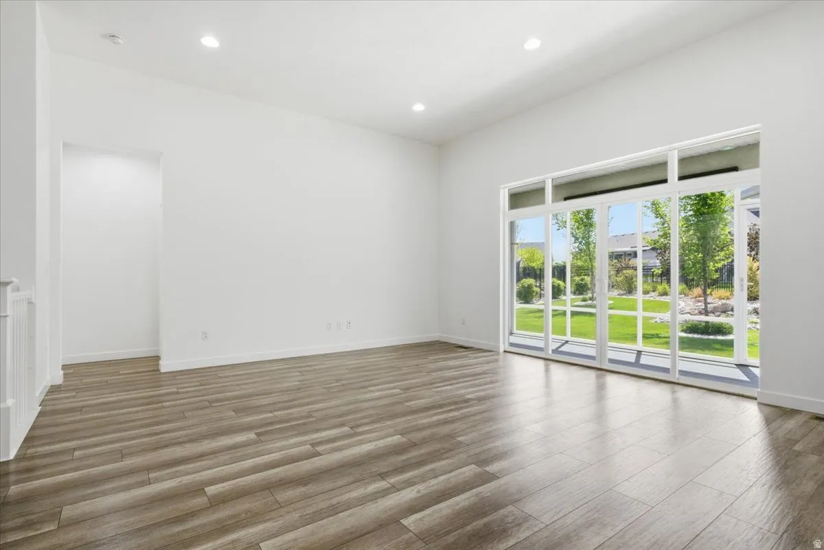 Spacious room featuring wood-finish flooring, recessed lighting, and a large sliding glass door