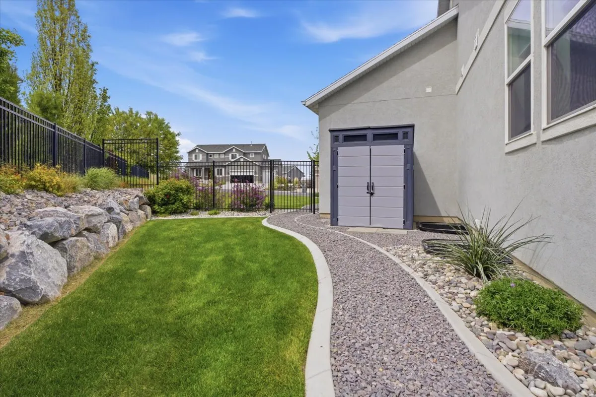 Side yard featuring a gravel pathway, rock landscaping, a built-in storage shed, and a privacy fence
