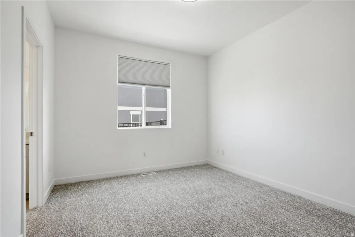 Carpeted room with a large window featuring a cellular shade, white walls, and white trim