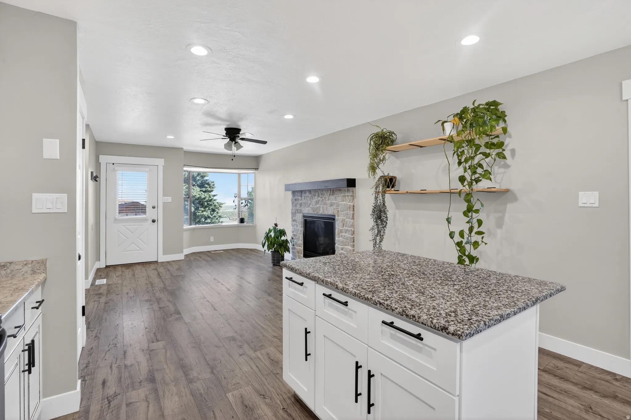 Kitchen island with granite-finish countertop and white cabinetry featuring black hardware