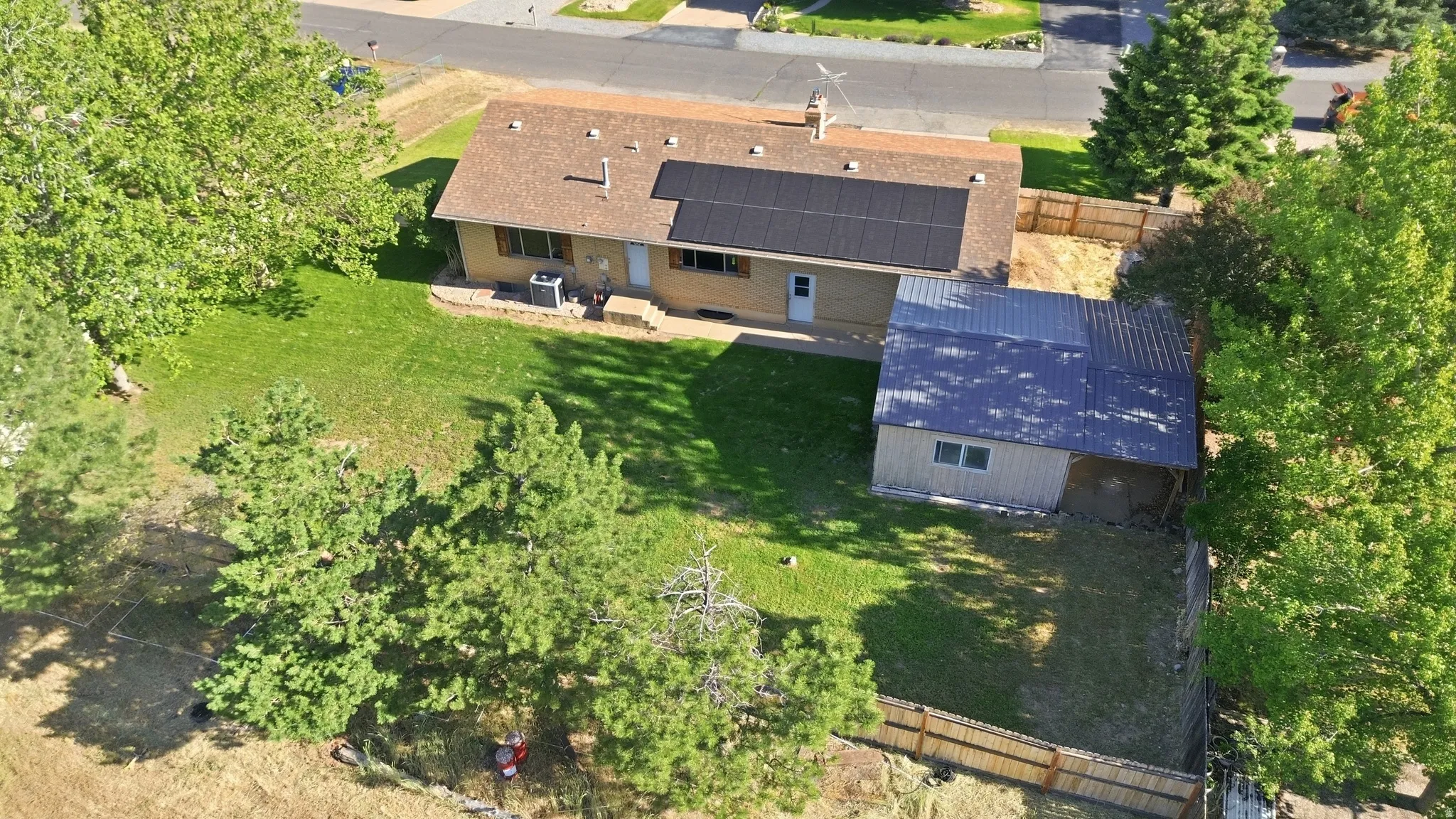 Expansive backyard featuring a manicured lawn, established trees, and a detached outbuilding with a metal roof