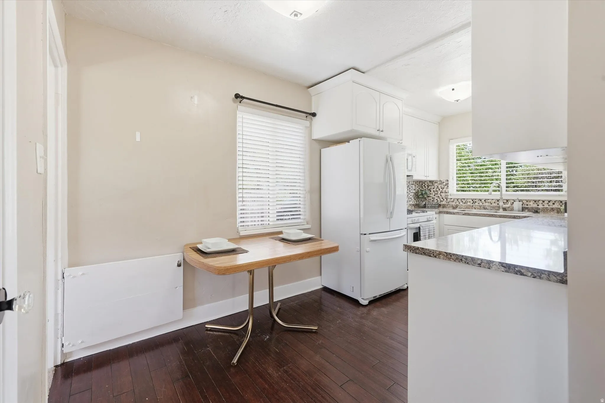 Kitchen area featuring wood-finish flooring, white cabinetry, and granite countertops