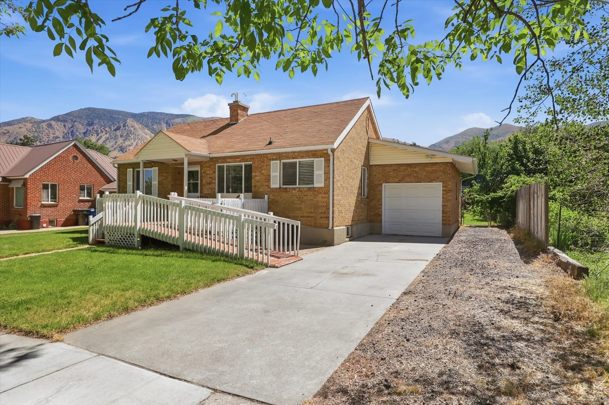 Brick-clad residence featuring a single-car garage, front entry ramp, and an extended driveway