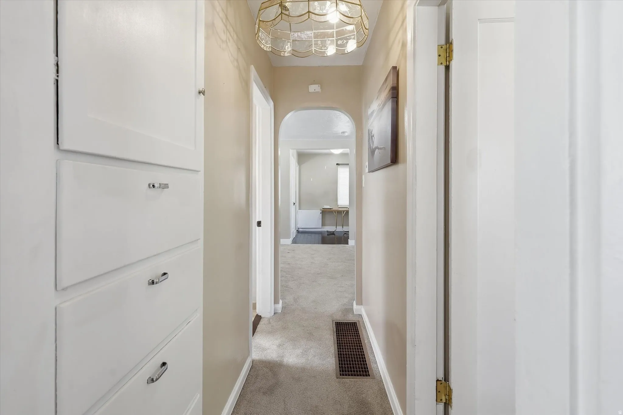 Hallway with built-in cabinetry, arched entryway, and laundry chute