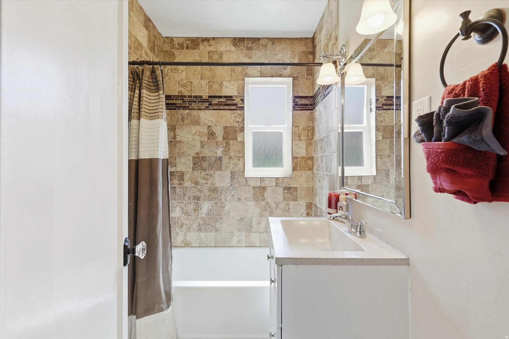 Bathroom with a vanity sink, wall-mounted mirror, and a built-in shower/tub combination