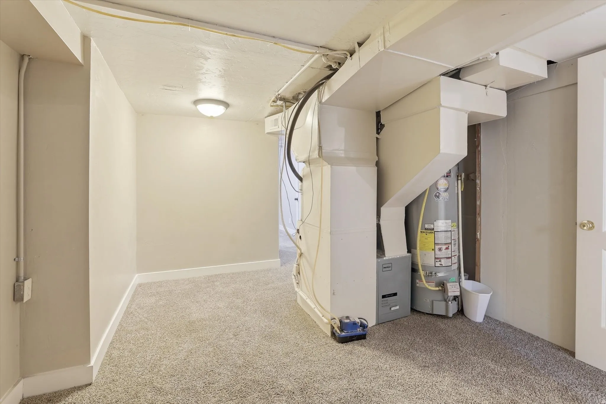 Utility area featuring a water heater, furnace, and exposed ductwork