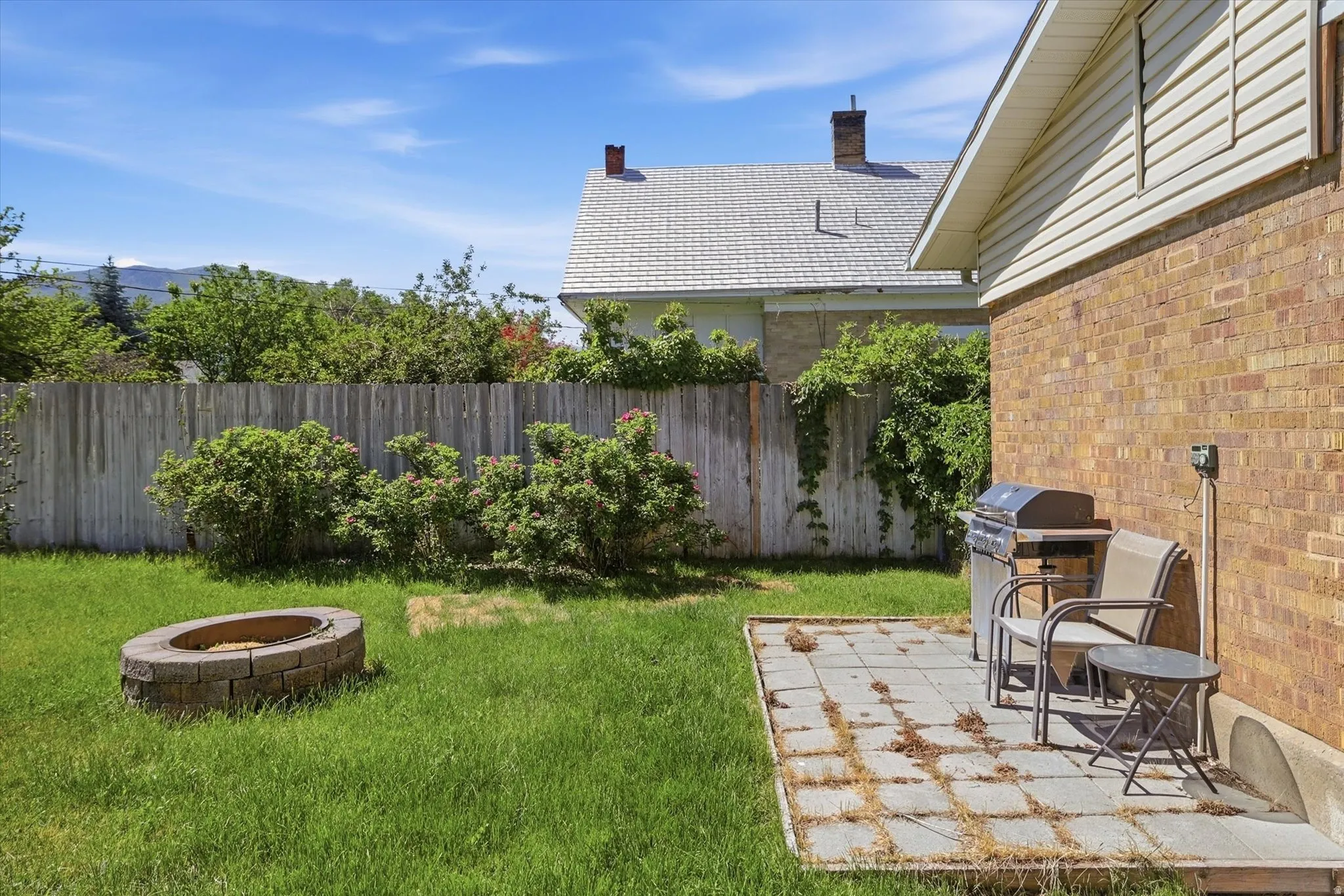 Backyard featuring a brick fire pit, wood privacy fence, and a paver patio area