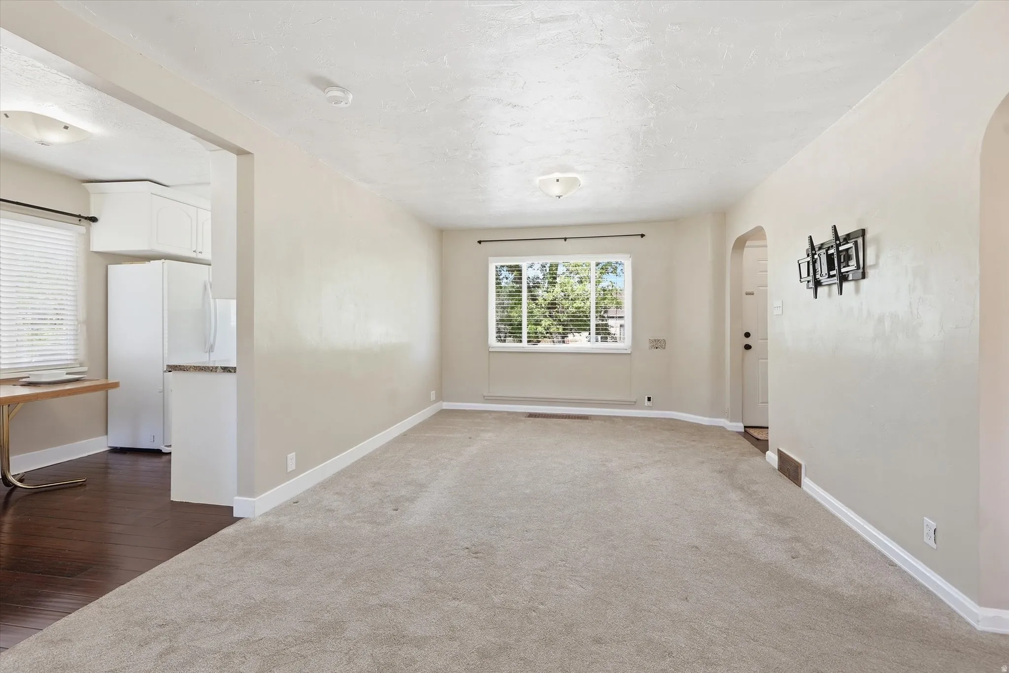 Spacious living area featuring neutral carpeting and a large window