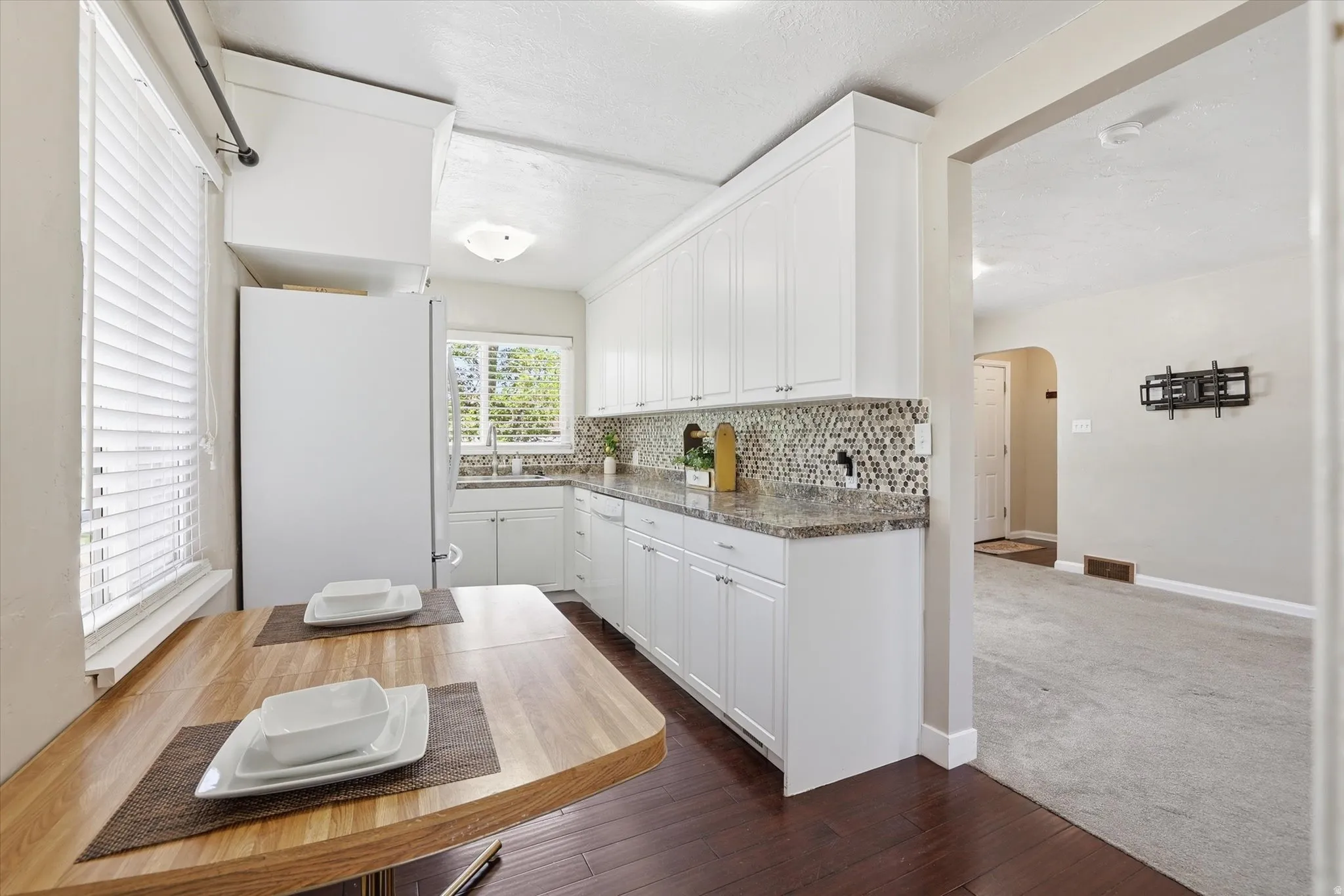 Kitchen with white cabinetry, granite countertops, and a mosaic tile backsplash