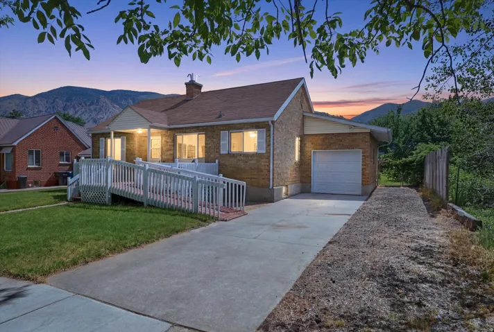 Brick exterior residence featuring a front porch with a white ramp, a one-car garage, and a concrete driveway