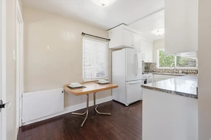 Kitchen area featuring wood-finish flooring, white cabinetry, and granite countertops
