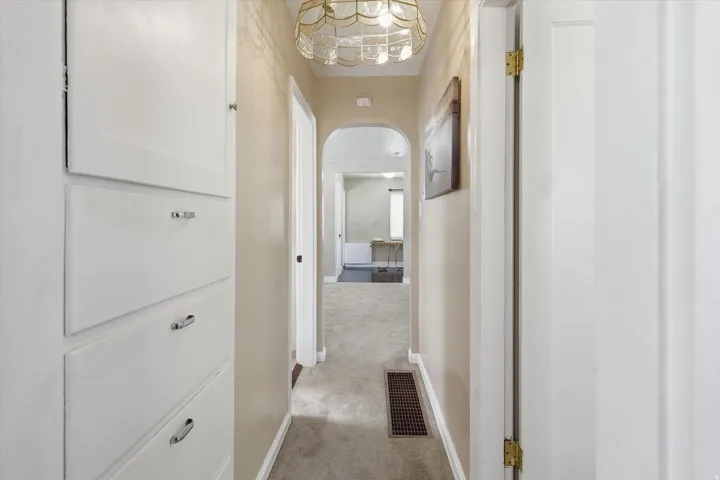 Hallway with built-in cabinetry, arched entryway, and laundry chute